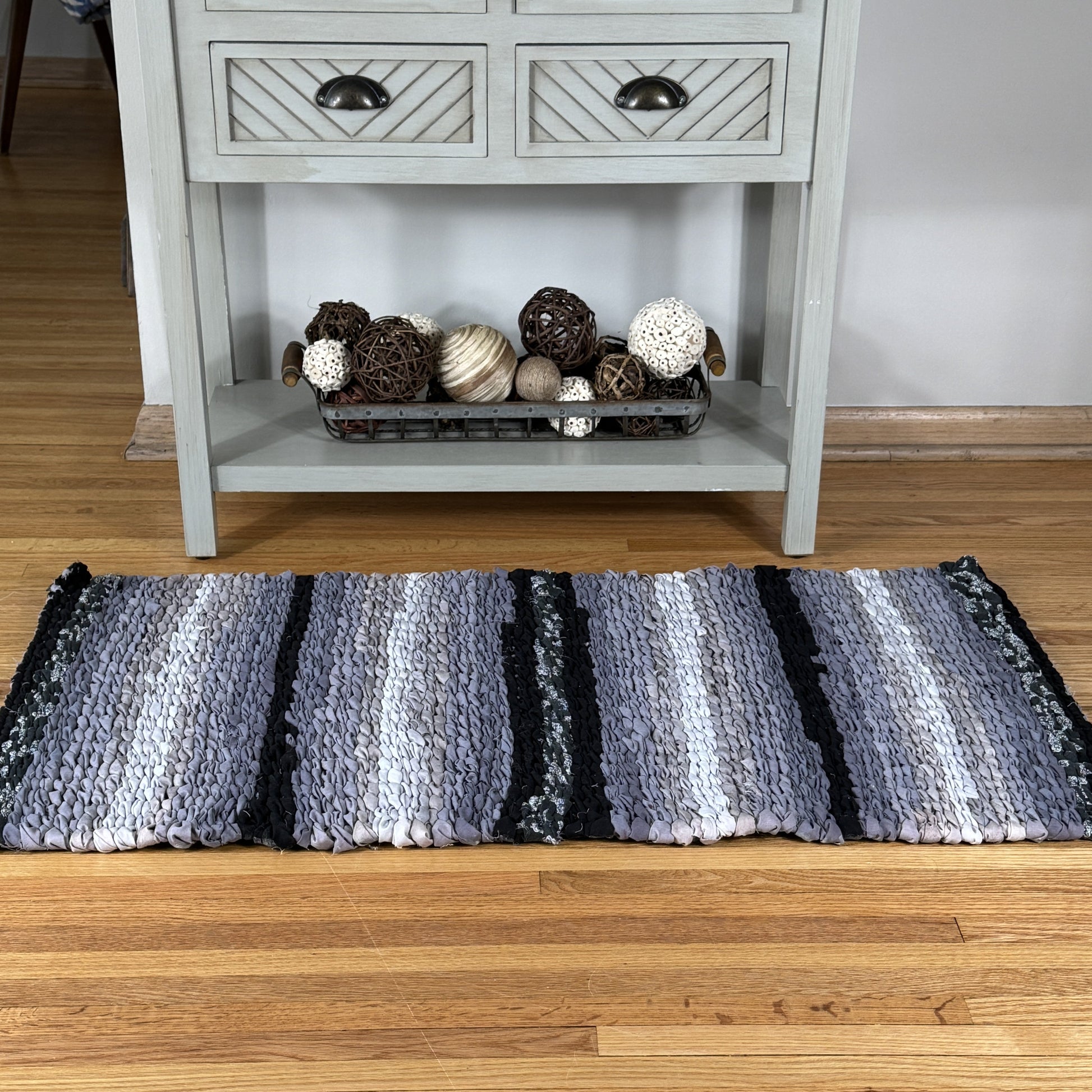 Striped rug on a wooden floor with a sideboard in the background