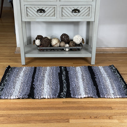 Striped rug on a wooden floor with a sideboard in the background
