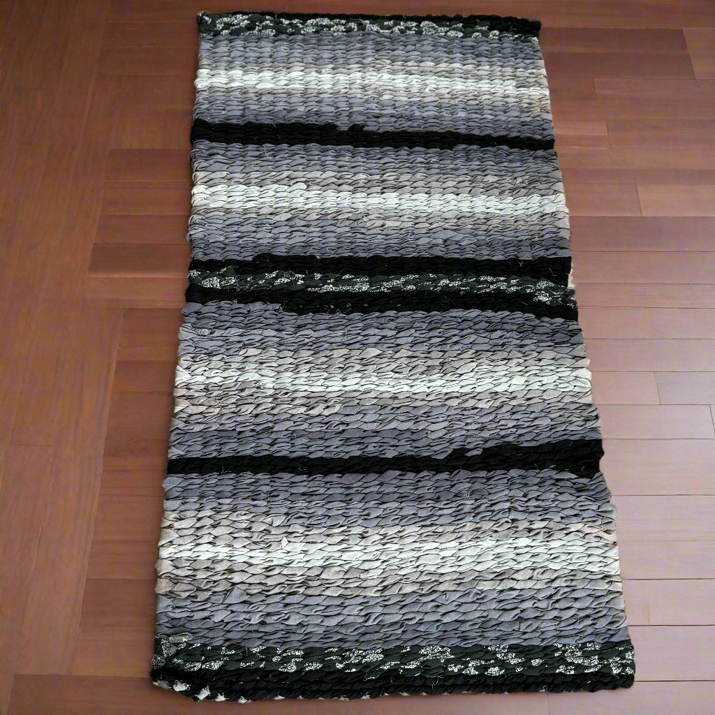 Striped rug with black, gray, and white pattern on a wooden floor