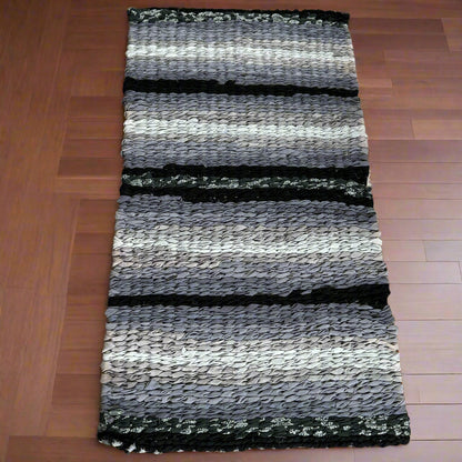 Striped rug with black, gray, and white pattern on a wooden floor